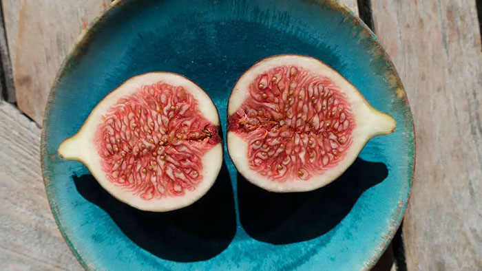 A fig cut in two halves on a blue plate
