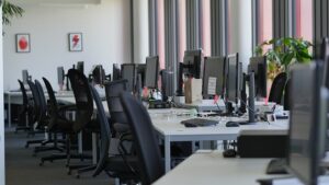Nowoczesna przestrzeń biurowa z komputerami i ergonomicznymi krzesłami.